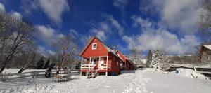czerwony dom pokryty śniegiem w obiekcie Domki że Hej Bieszczady w mieście Ustrzyki Dolne