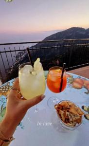 uma pessoa a segurar duas bebidas numa mesa em Le Marelle em Furore