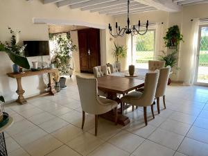 a dining room with a wooden table and chairs at Le Mas aux Papillons in Vendat