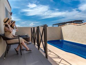 duas mulheres sentadas numa varanda ao lado de uma piscina em Ocean's Resort Villa Vorla - Vacation STAY 36094v em Arazato