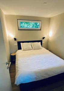 sypialnia z dużym białym łóżkiem i oknem w obiekcie Oosterschelde Lodge met veel privacy en dicht bij het water w mieście Scherpenisse