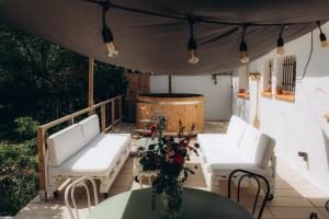 un patio con 2 sillas blancas y una mesa con flores en Gîtes Chaleureux écoresponsable, en Montesquieu-Lauragais