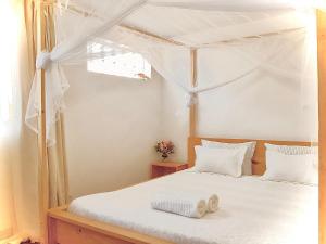 a bedroom with a canopy bed with white sheets at Villa ChezSoa, Antananarivo in Antananarivo