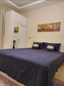 a bedroom with a large blue bed with two pillows at Juman B&B in Seeb