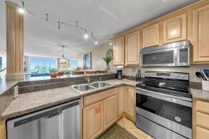 a kitchen with wooden cabinets and stainless steel appliances at Destin on the Gulf 205 - Updated Gulf Front Property with Free Beach Service in Destin