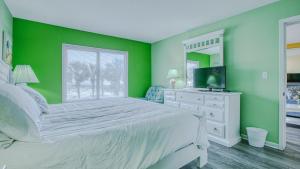 a green bedroom with a bed and a television at Destin on the Gulf 201 - Beach Front Property in Destin +8 photos