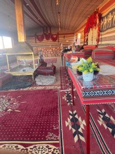 salon z czerwonymi stołami i czerwonym dywanem w obiekcie Omar Ghazi Camp w mieście Wadi Rum