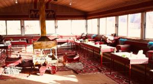 a room with red chairs and tables and windows at Omar Ghazi Camp in Wadi Rum