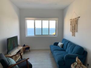 a living room with a blue couch and a window at Casa do Porto, relax with this stunning sea view in Porto Formoso