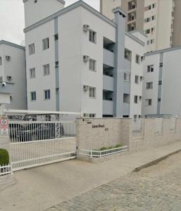 a large white building with a fence in front of it at Quarto solteiro em brusque in Brusque
