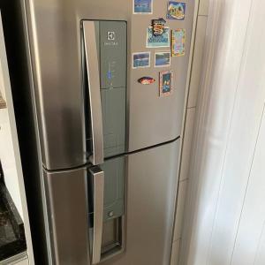 a stainless steel refrigerator with magnets and pictures on it at Quarto solteiro em brusque in Brusque