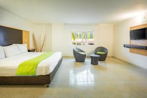 a hotel room with a bed and two chairs at Hotel Americas San Andres Islas Colombia in San Andrés