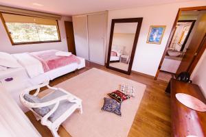 ein Schlafzimmer mit einem Bett, einem Stuhl und einem Spiegel in der Unterkunft Casa Rosa - Terra Dourada, Paraíso na Natureza in Brasilia
