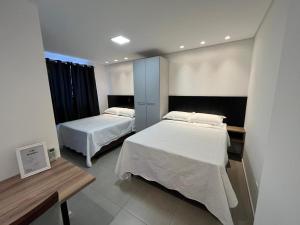 a hotel room with two beds and a desk and sidx sidx sidx at Loft com vista para Vila Germânica 603 in Blumenau