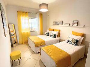 Zimmer mit 2 Betten, gelber Bettwäsche und einem Stuhl in der Unterkunft Praia Village AG in Vilamoura