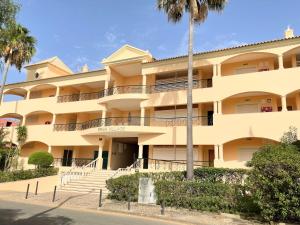 a large yellow building with palm trees in front of it at Praia Village AG in Vilamoura