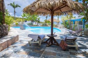 a patio with chairs and an umbrella and a swimming pool at Résidence Vue Mer in Deshaies