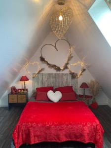 - une chambre avec un lit rouge et deux cœurs sur le mur dans l'établissement gite l'etoile de mer, à Eu