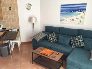 a living room with a blue couch and a table at El Carmen in El Cotillo +25 photos