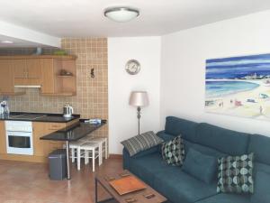 a living room with a blue couch and a kitchen at El Carmen in El Cotillo
