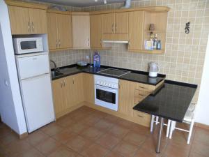 a kitchen with wooden cabinets and a white refrigerator at El Carmen in El Cotillo