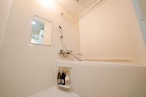 a white bathroom with a mirror and bottles of wine at FL Rejidence Shinjuku 2 - Vacation STAY 15199 in Tokyo
