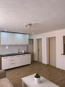 a kitchen with white cabinets and a living room at Lejla's guesthouse in Gusinje