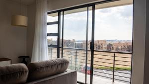 a room with a couch and a large window at Lush Studio Apartment with Back-Up Power. in Sandton