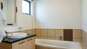 a bathroom with a sink and a bath tub at Lush Studio Apartment with Back-Up Power. in Sandton