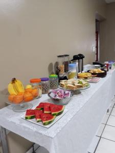 una mesa con platos de comida y fruta. en Lurviz Home Suítes, en Cabo Frío