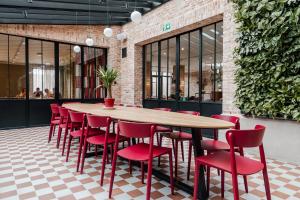 een houten tafel en rode stoelen in een restaurant bij Hotel T in Waregem
