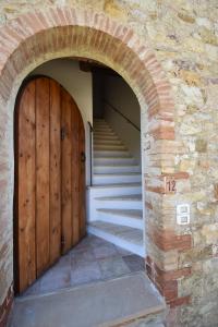 an archway with two wooden doors and stairs at Borgo Mulignone in Casole dʼElsa