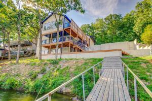 a house on top of a hill with a wooden staircase at Lakefront Osage Beach Retreat Floating Swim Dock! in Osage Beach