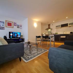 a living room with a couch and a table and a kitchen at Exquisite One Bedroom Apartment in the Heart of Sheffield City Centre in Sheffield