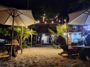 a beach with tables and umbrellas on the sand at night at El Almendrón Beach Hostel in Santa Marta