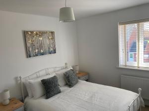 Un dormitorio con una cama blanca y una foto en la pared en The Belfry 3 Bedrooms 2 Bathrooms Contractors & Family en Higham Ferrers
