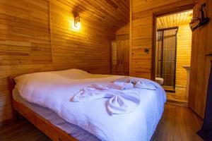 Reflections Camp في فاراليا: سرير في غرفة خشبية عليها مناشف