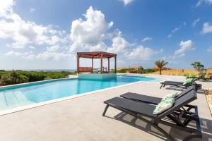 a swimming pool with a gazebo and two lounge chairs at Coral Estate Ocean View Apartments in Willemstad