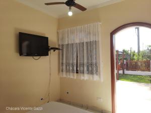 ein Wohnzimmer mit einem TV und einem Fenster in der Unterkunft Chácara Vicente Gazzi in Socorro