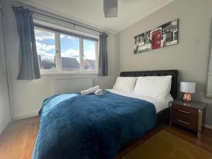 ein Schlafzimmer mit einem Bett mit einer blauen Decke und einem Fenster in der Unterkunft FilmonHomes in Oldbury