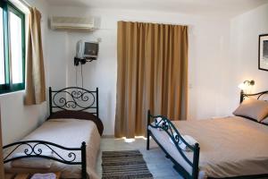 a bedroom with two beds and a window at Gefyra Rooms in Ancient Epidauros