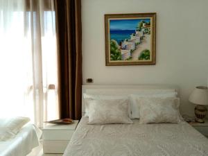 una camera con un letto bianco e una foto appesa al muro di Guest room near historical center a Vlorë