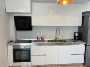 La cuisine est équipée de placards blancs, d'un évier et d'une cuisinière. dans l'établissement Adelina's Delux Apartament Durres, à Durrës
