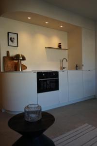 uma cozinha com armários brancos, um lavatório e uma mesa em Studio23 Knokke em Knokke-Heist