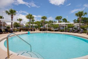 a large swimming pool with chairs and palm trees at Ocean Antics - Close to the Beach and minutes to Seaside along 30A in Santa Rosa Beach
