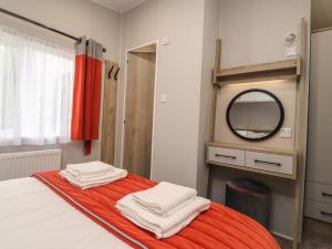 a bedroom with a bed with an orange blanket and a mirror at Astoria Lodge in Clitheroe