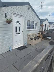 une maison blanche avec une porte blanche et un banc dans l'établissement Sanity Sanctuary, à Leysdown-on-Sea
