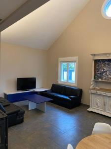 ein Wohnzimmer mit einem schwarzen Sofa und einem TV in der Unterkunft Maison ossature bois in Dole