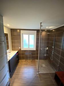 ein Bad mit einer Dusche, einem Waschbecken und einem Fenster in der Unterkunft Maison ossature bois in Dole