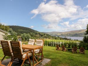 a wooden table and chairs on a lawn with a view at Beech Cottage in Aberfeldy